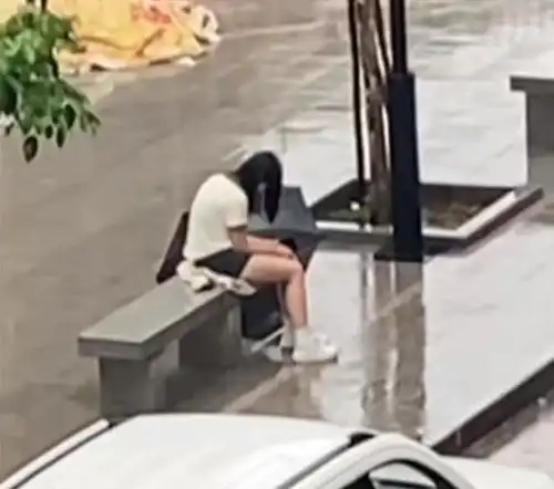 广东一女子失恋太伤心,独自坐在街头淋雨,男子好心送伞也不理会
